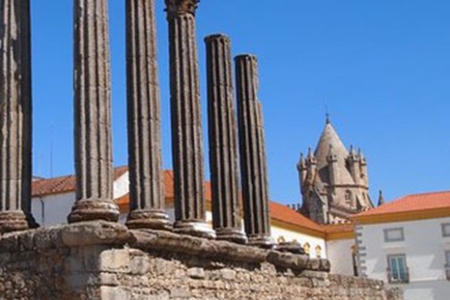 Ancient stone temple ruins with tall columns, clear blue sky.