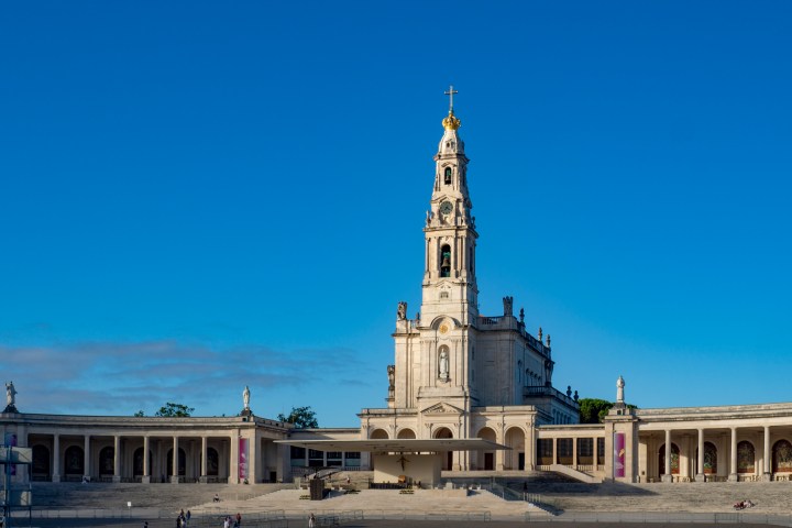 A grand cathedral with archways and a tall central tower under a clear blue sky.