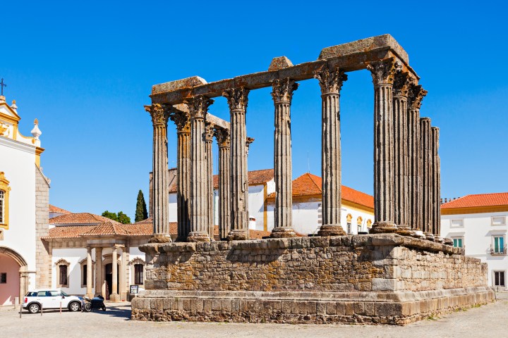 Ancient stone temple ruins with tall columns under a clear blue sky.
