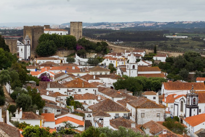 Panoramic view of a historic town with white buildings and a castle on a hill.